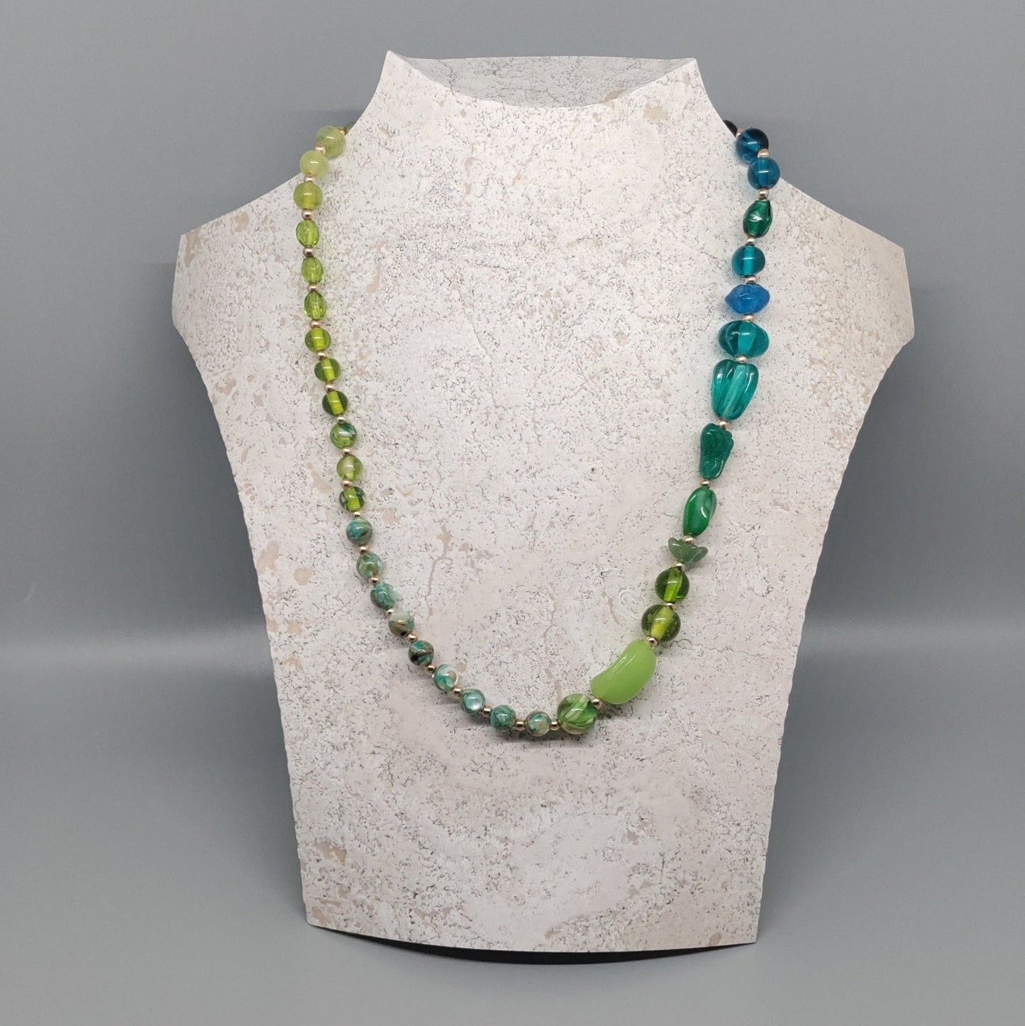 Necklace displayed on a mannequin bust against a gray background
