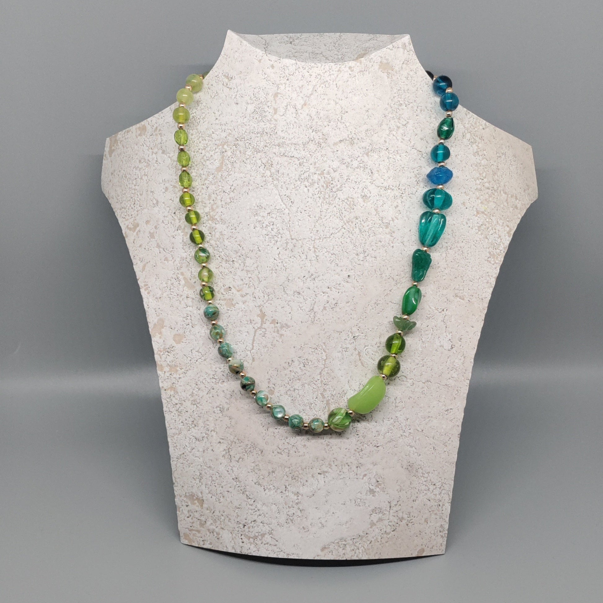Necklace displayed on a mannequin bust against a gray background