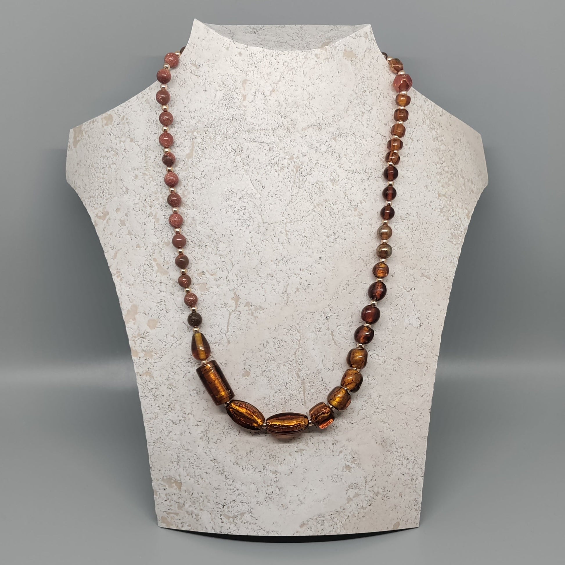 Beaded necklace on a mannequin bust against a gray background