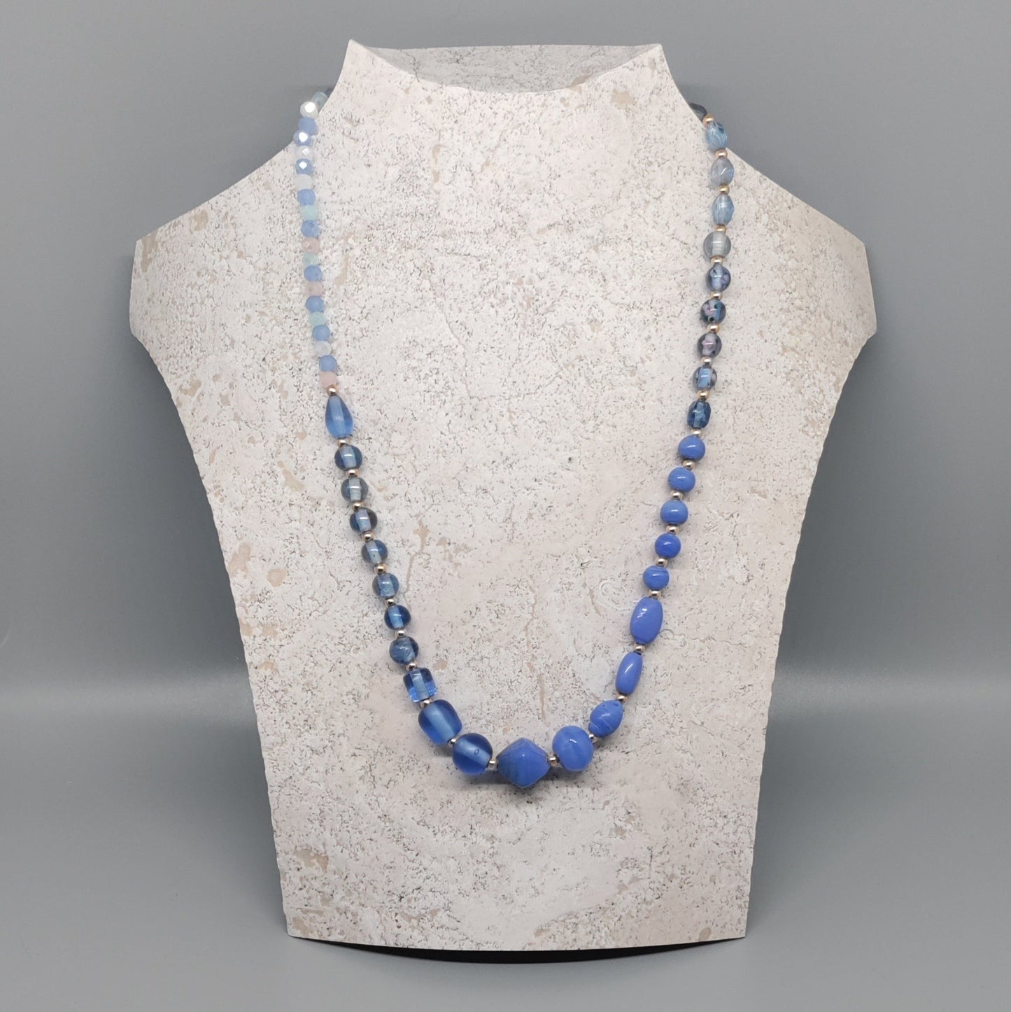 Necklace with blue beads on a mannequin bust against a gray background
