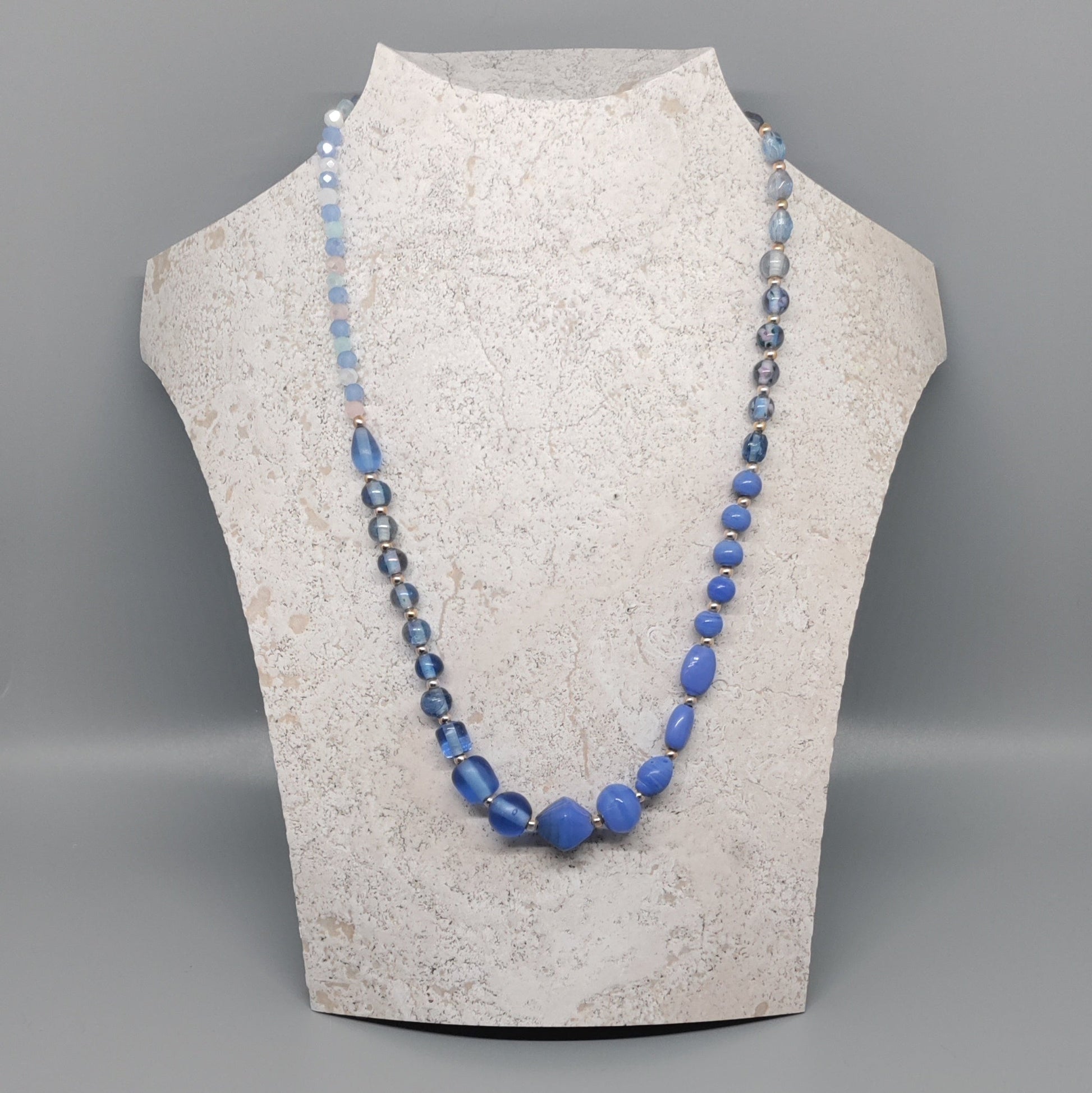Necklace with blue beads on a mannequin bust against a gray background