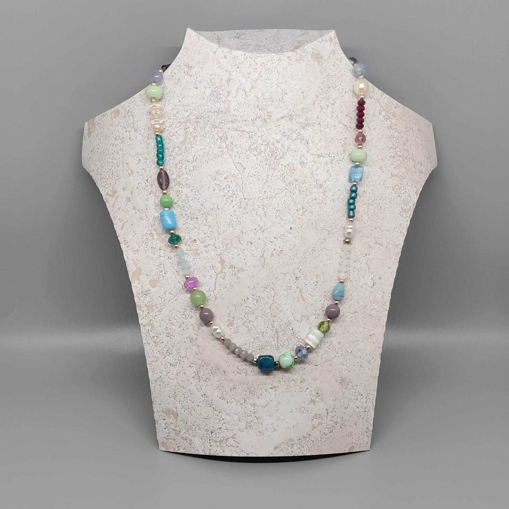 Necklace on a mannequin bust against a gray background