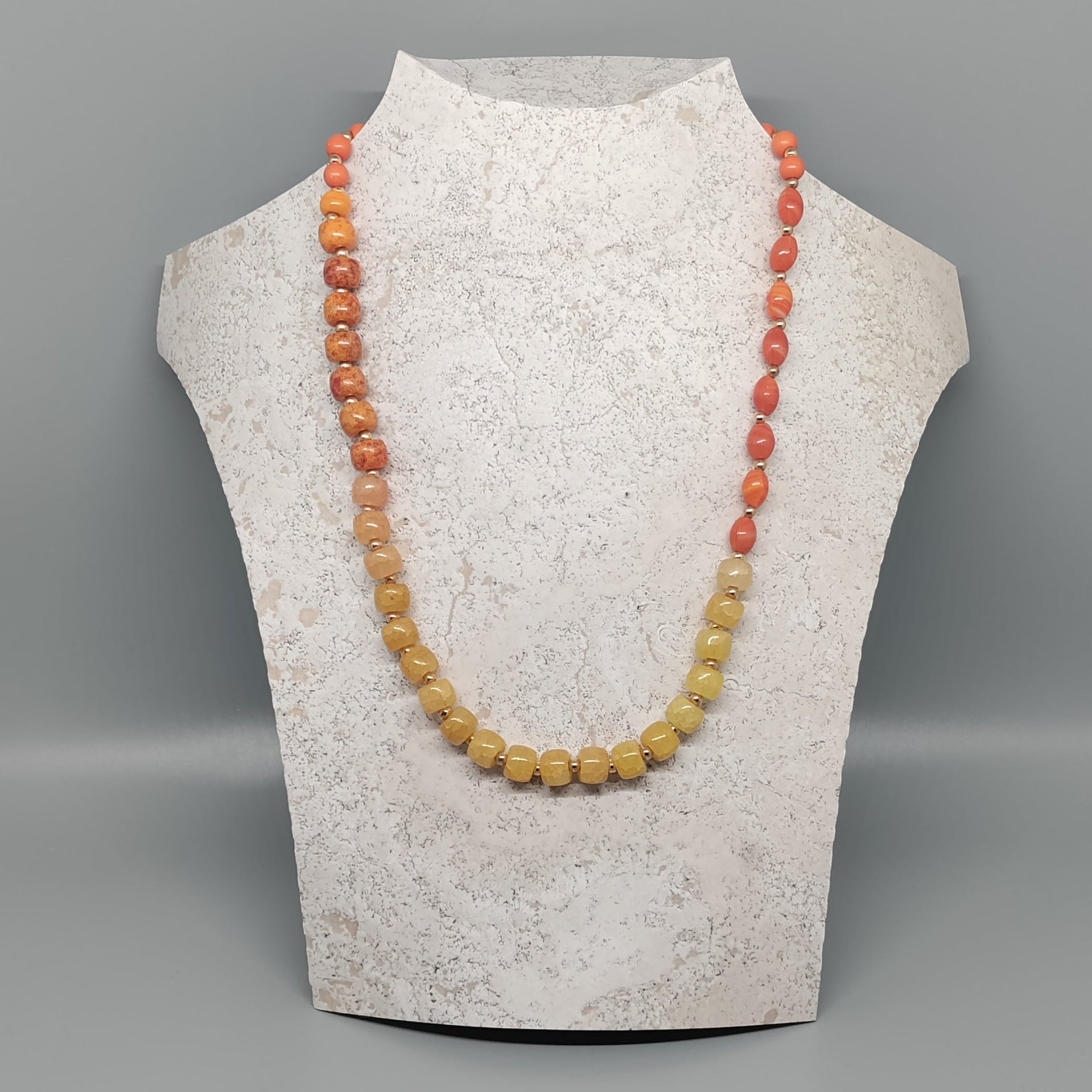 Necklace displayed on a mannequin bust against a gray background