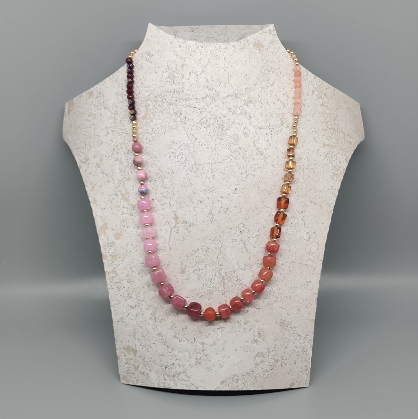 Necklace with multicolored beads on a mannequin bust against a gray background