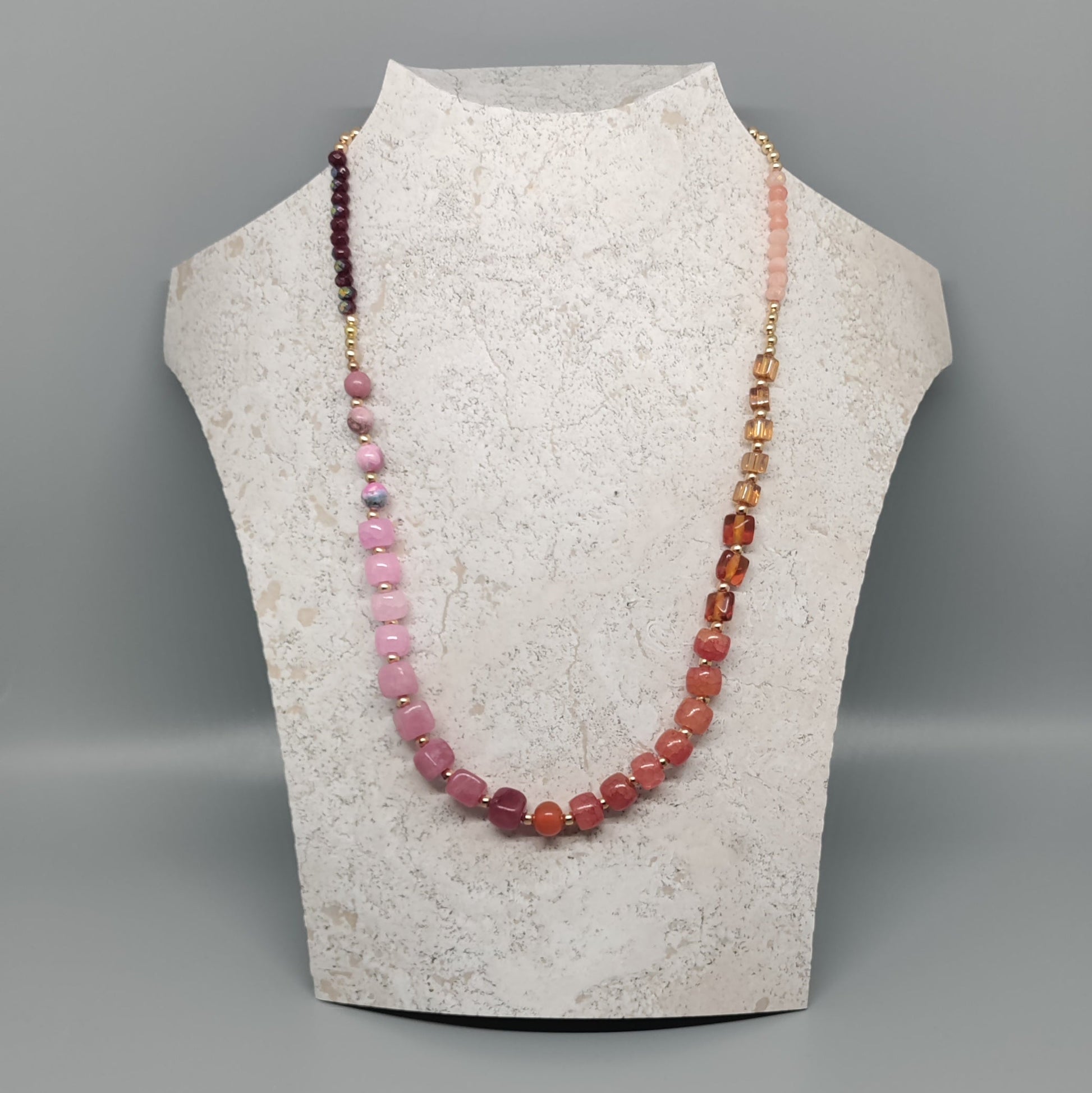 Necklace with multicolored beads on a mannequin bust against a gray background