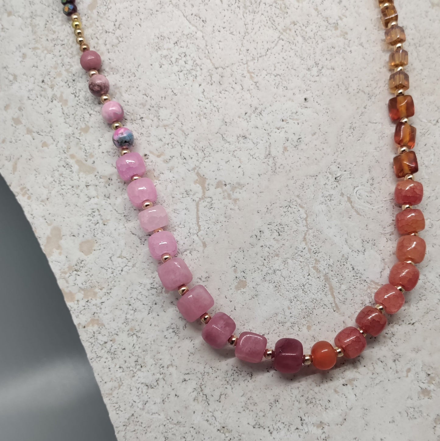 Necklace with multicolored beads on a textured white stand