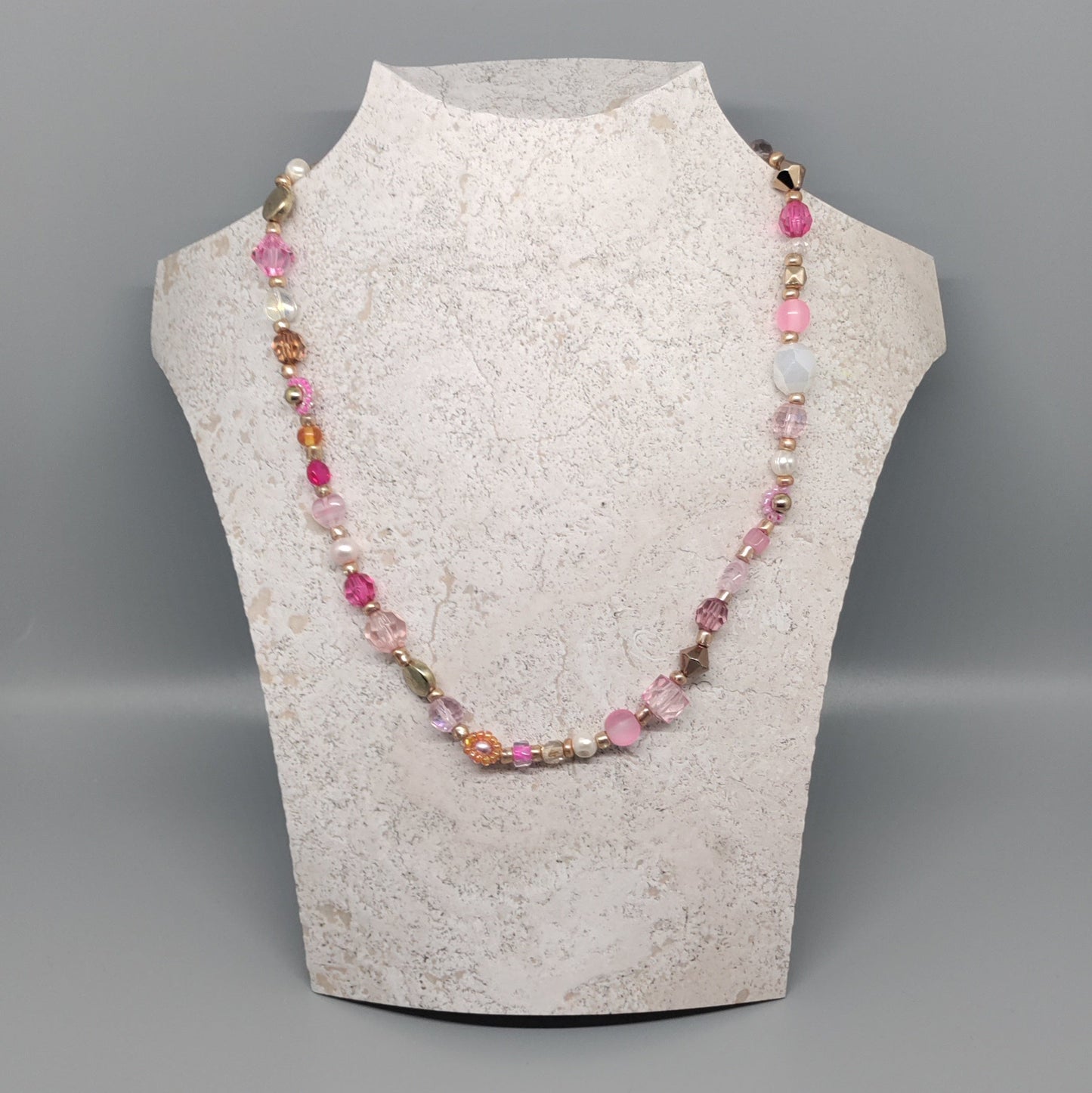 Necklace on a mannequin bust against a gray background