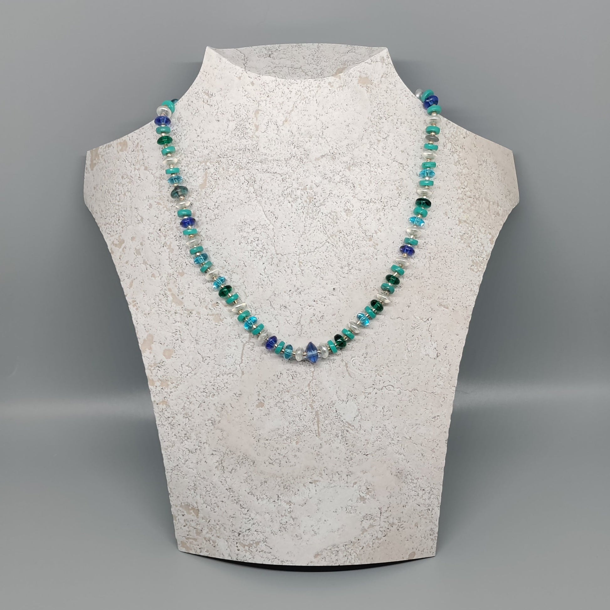 Necklace on a mannequin bust against a gray background