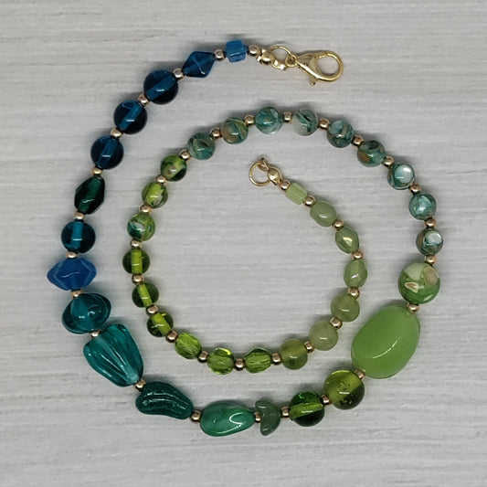 Blue and green beaded necklace on a textured gray surface
