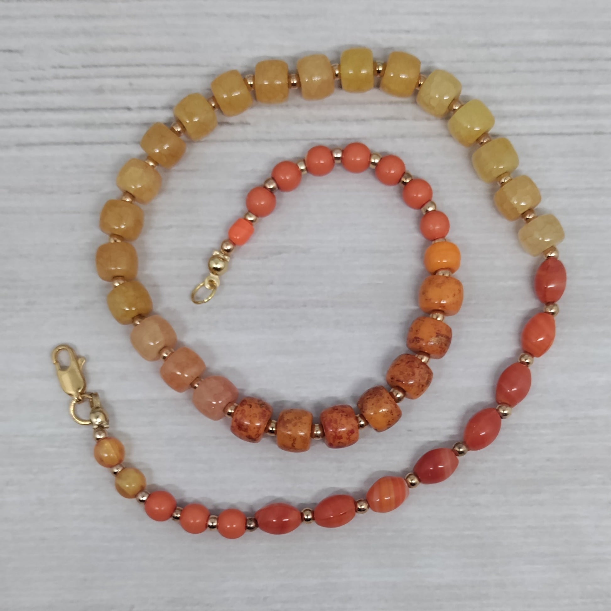 Orange and yellow beaded necklace on a textured gray surface
