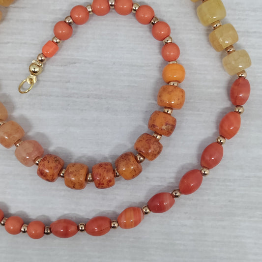 Orange and yellow beaded necklace on a textured gray surface