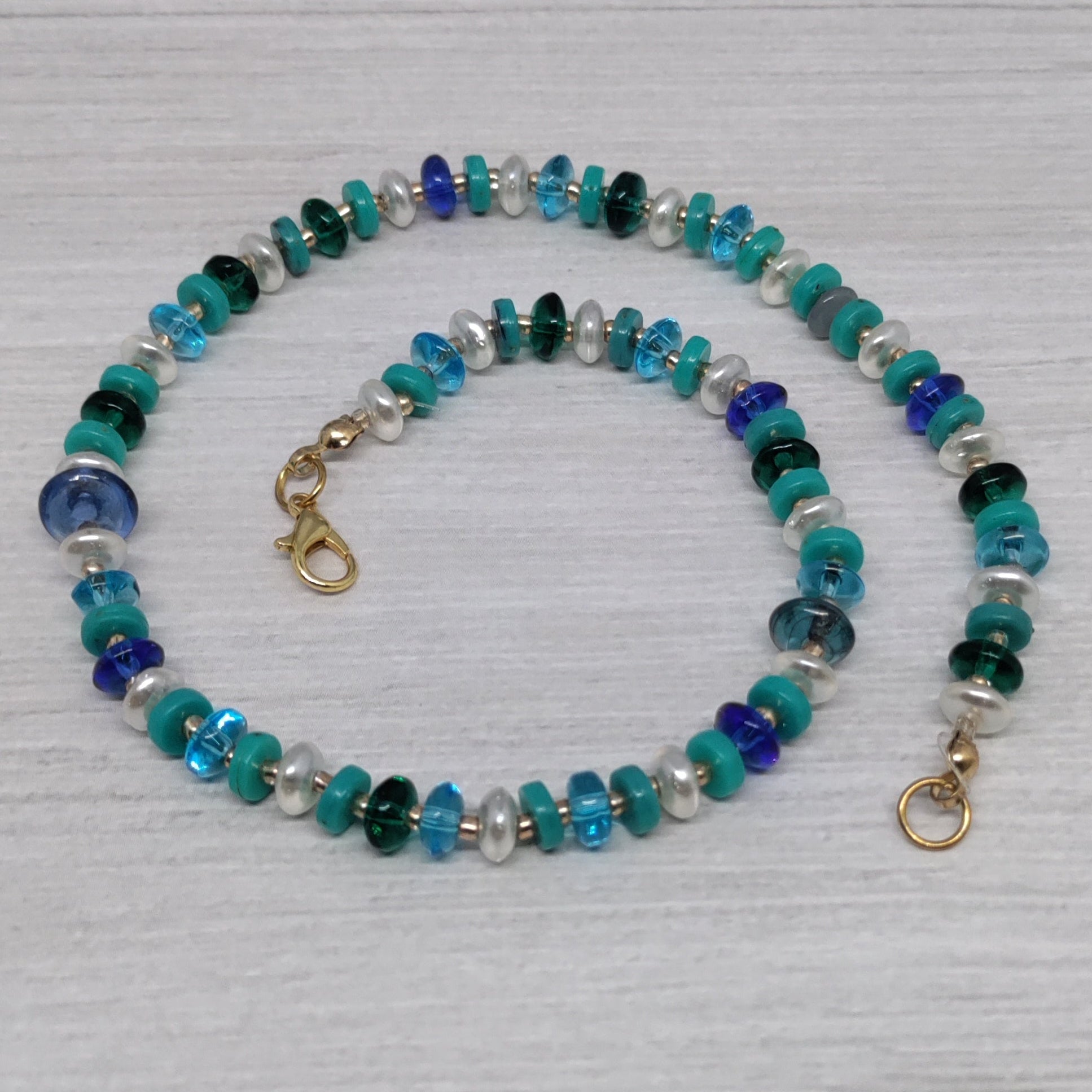 Beaded necklace with blue and green stones on a light wooden surface