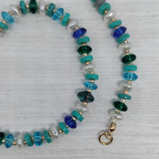 Necklace with blue, green, and silver beads on a light gray background