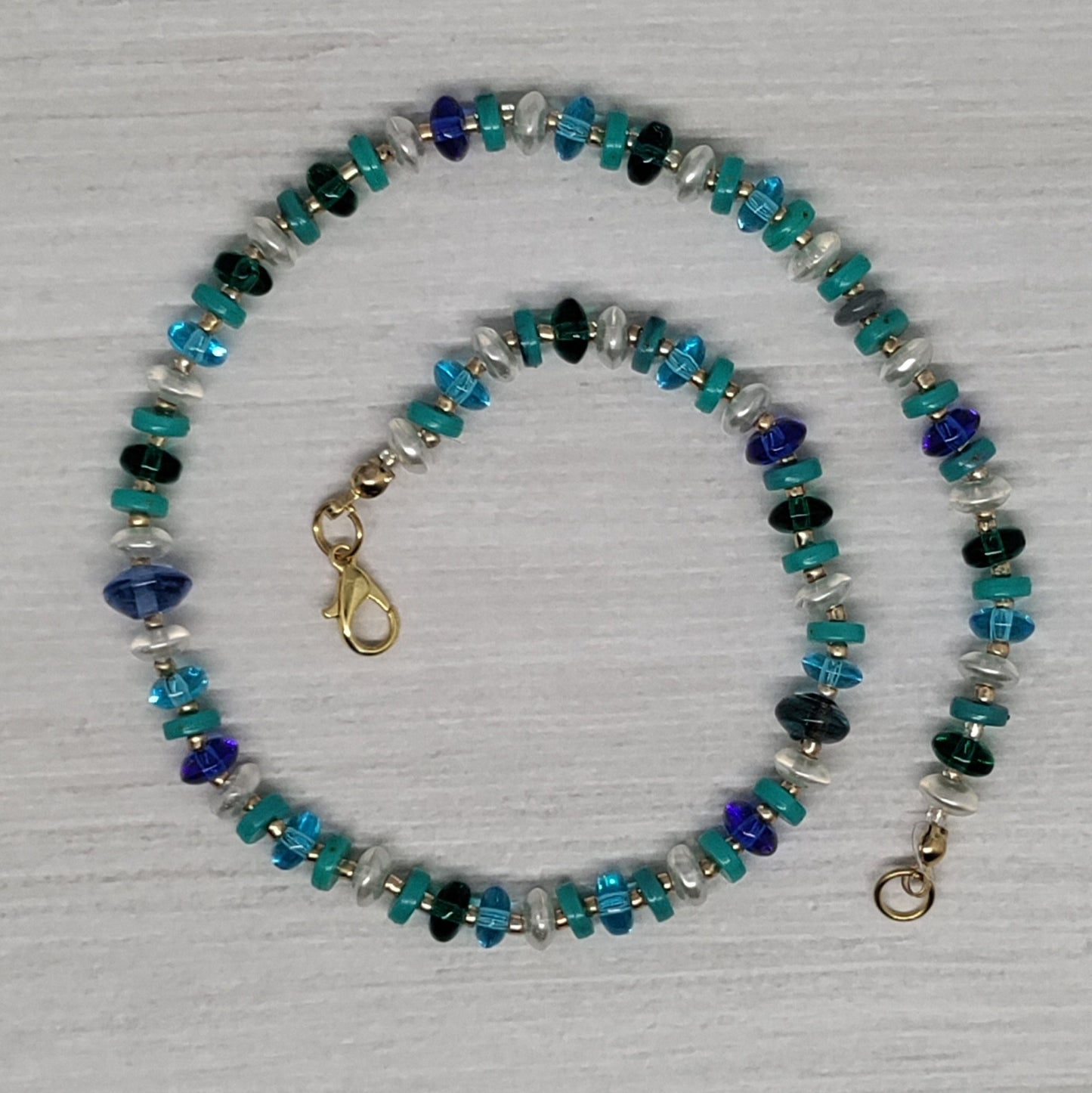 Beaded necklace with blue and green stones on a light gray background