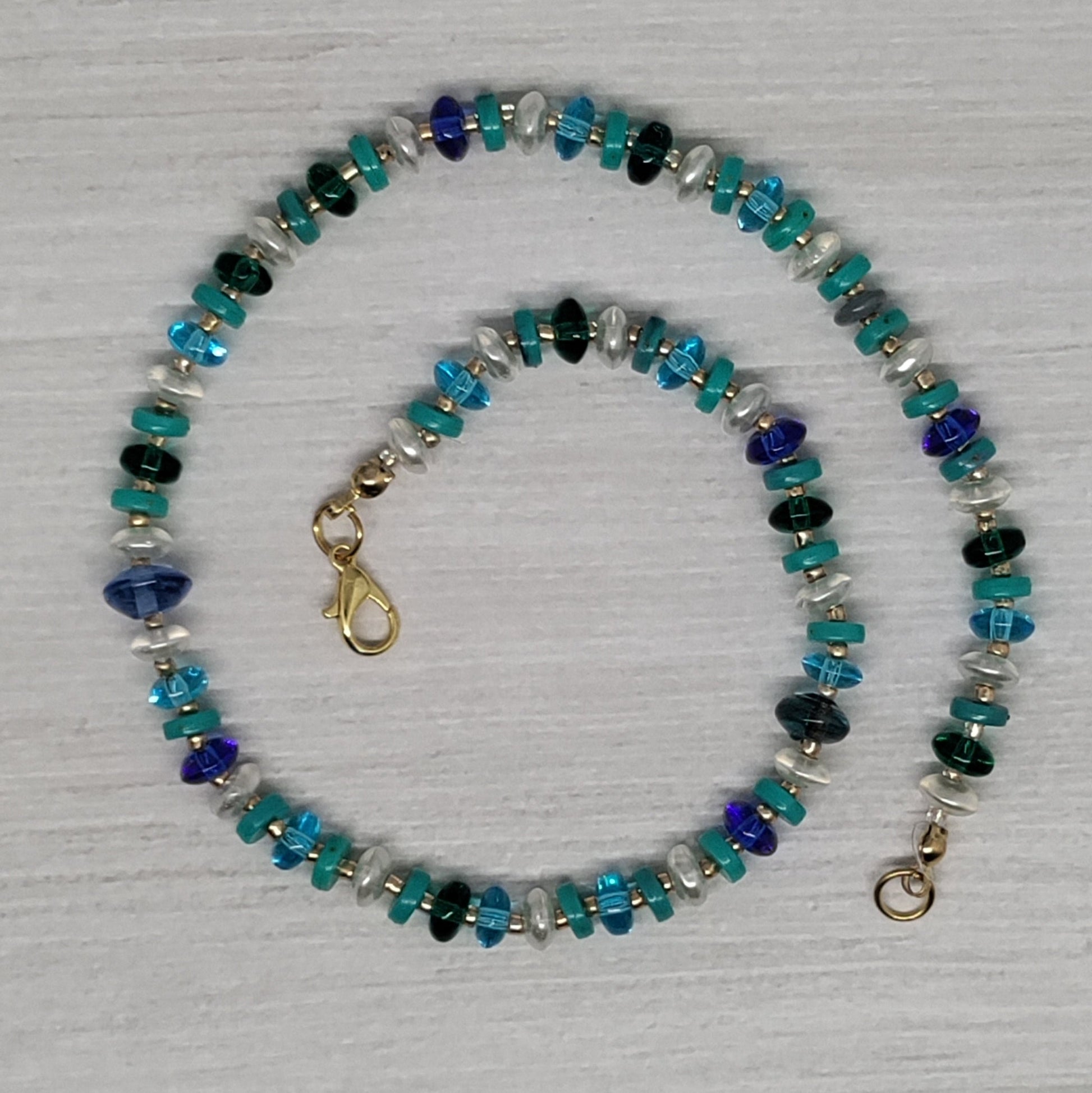Beaded necklace with blue and green stones on a light gray background