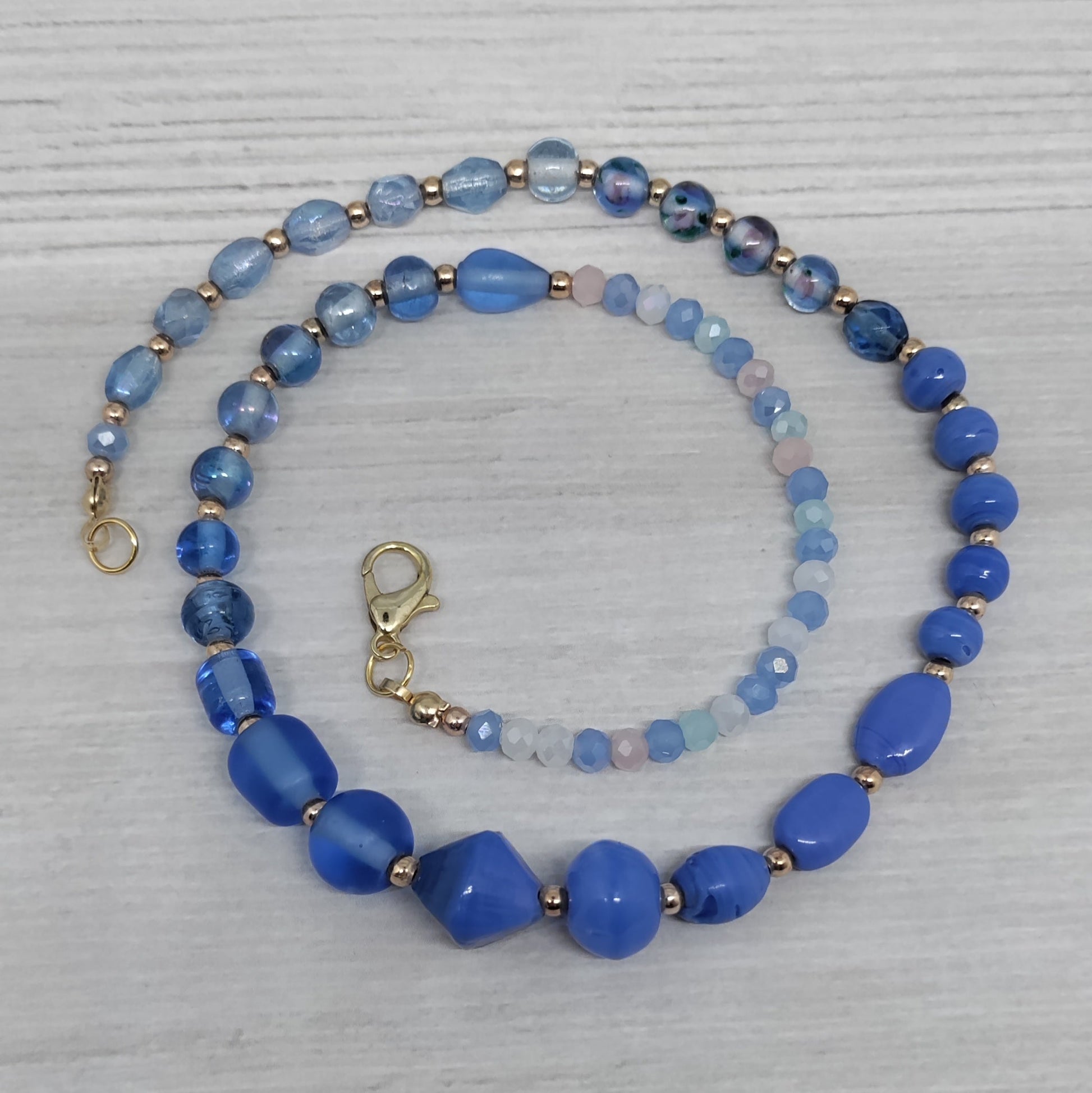 Blue beaded necklace on a light gray surface