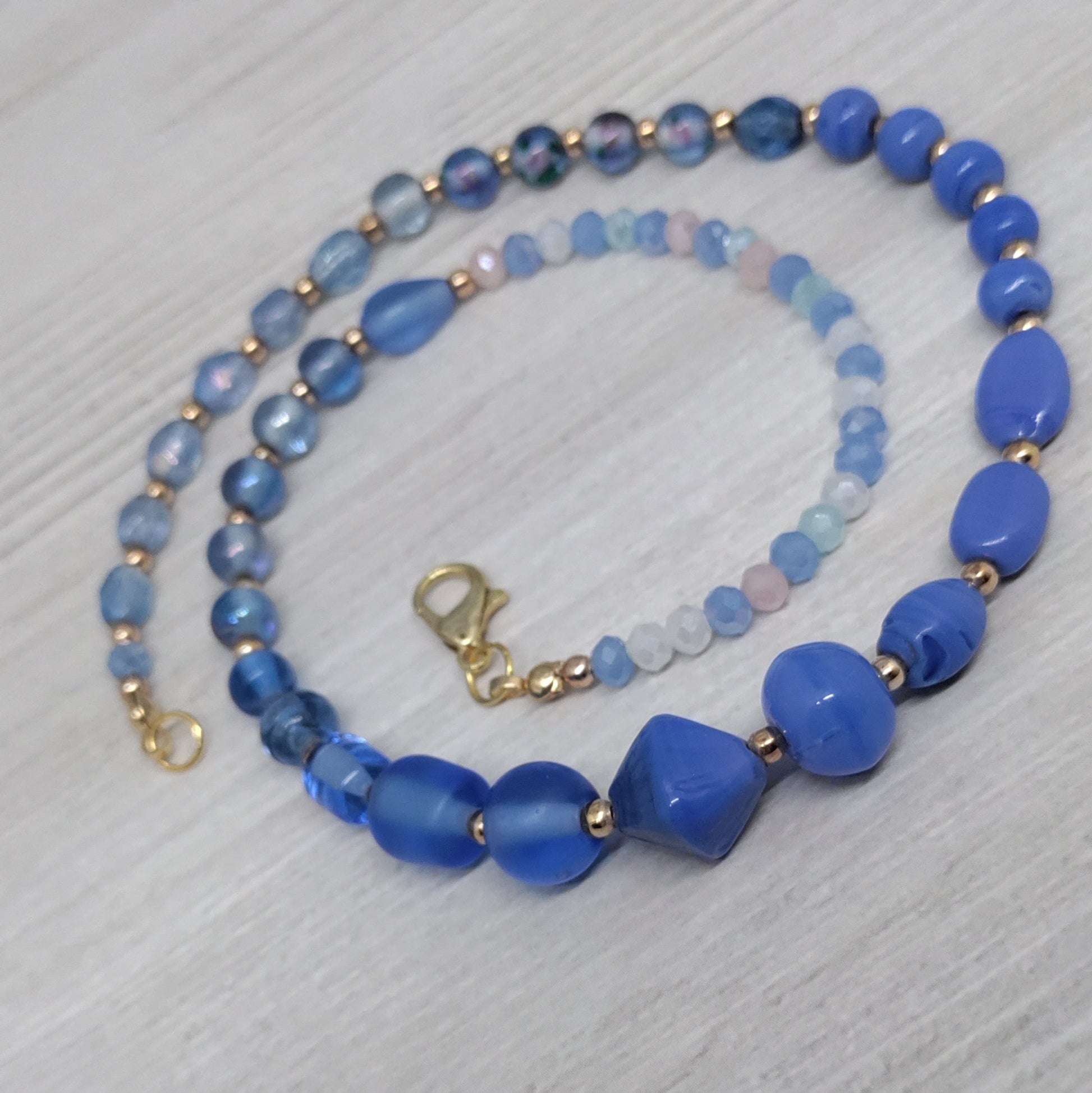 Blue beaded necklace on a light gray surface
