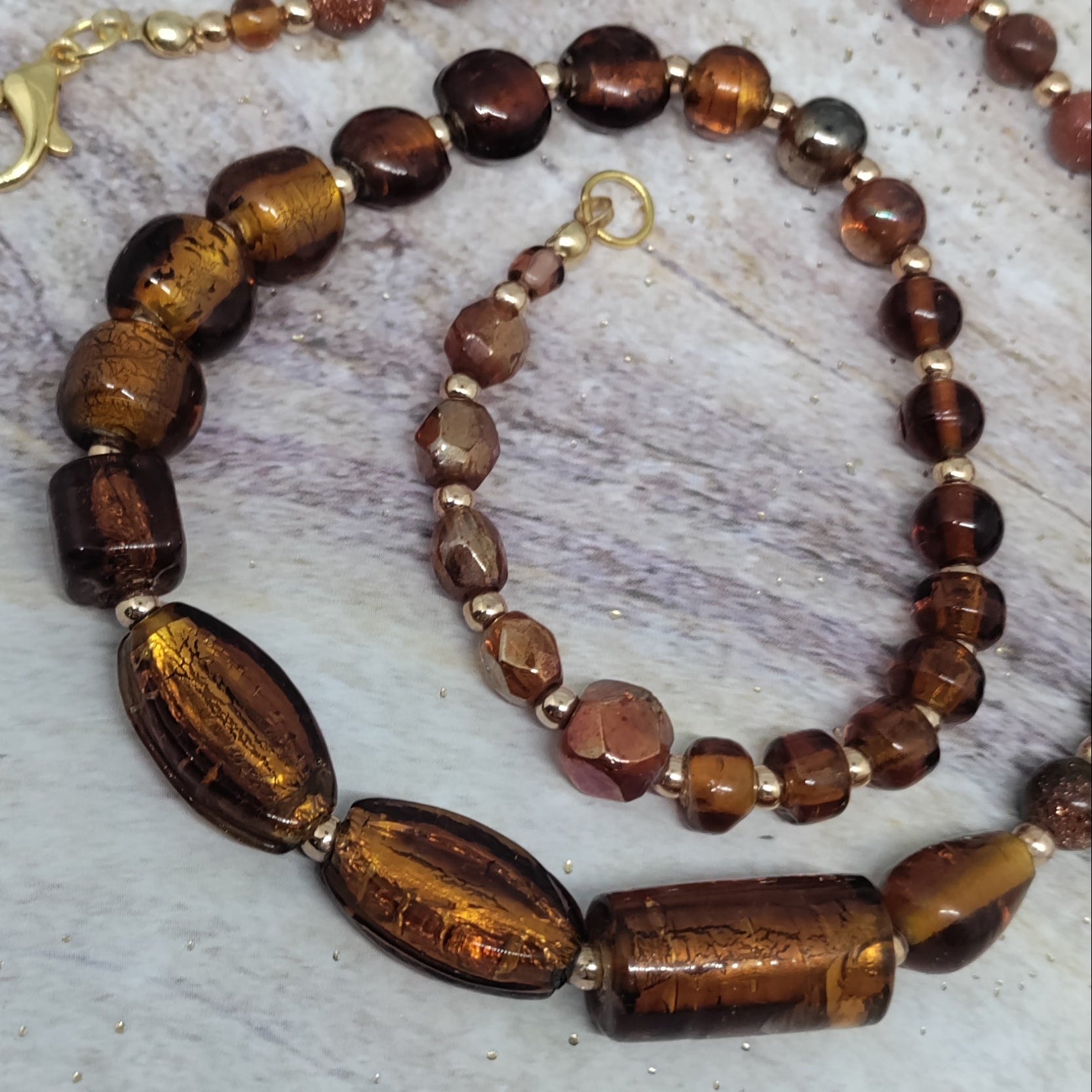 Necklace with brown and gold beads on a textured surface