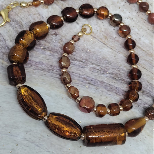 Necklace with brown and gold beads on a textured surface