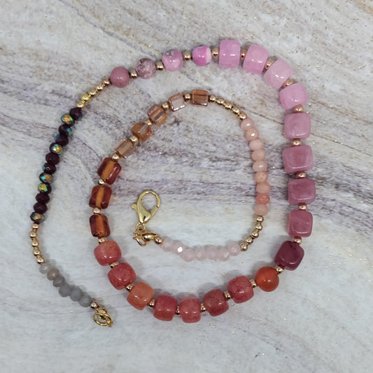 Beaded necklace with pink and red beads on a textured surface