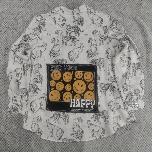 A white long-sleeve button-up shirt with a black line art print of various cats, featuring a central black patch with yellow smiley faces and the text 'FIND YOUR HAPPY'. The shirt is laid flat on a textured gray fabric background.