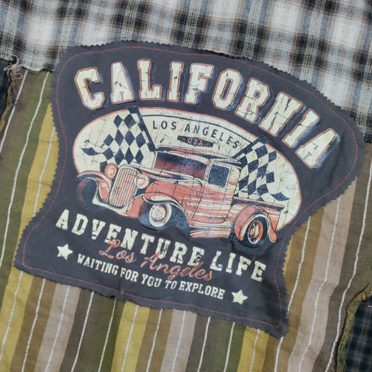 A close-up of a vintage-style patch with the words "CALIFORNIA ADVENTURE LIFE Los Angeles" and an illustration of a red truck, sewn onto a striped and plaid fabric garment.
