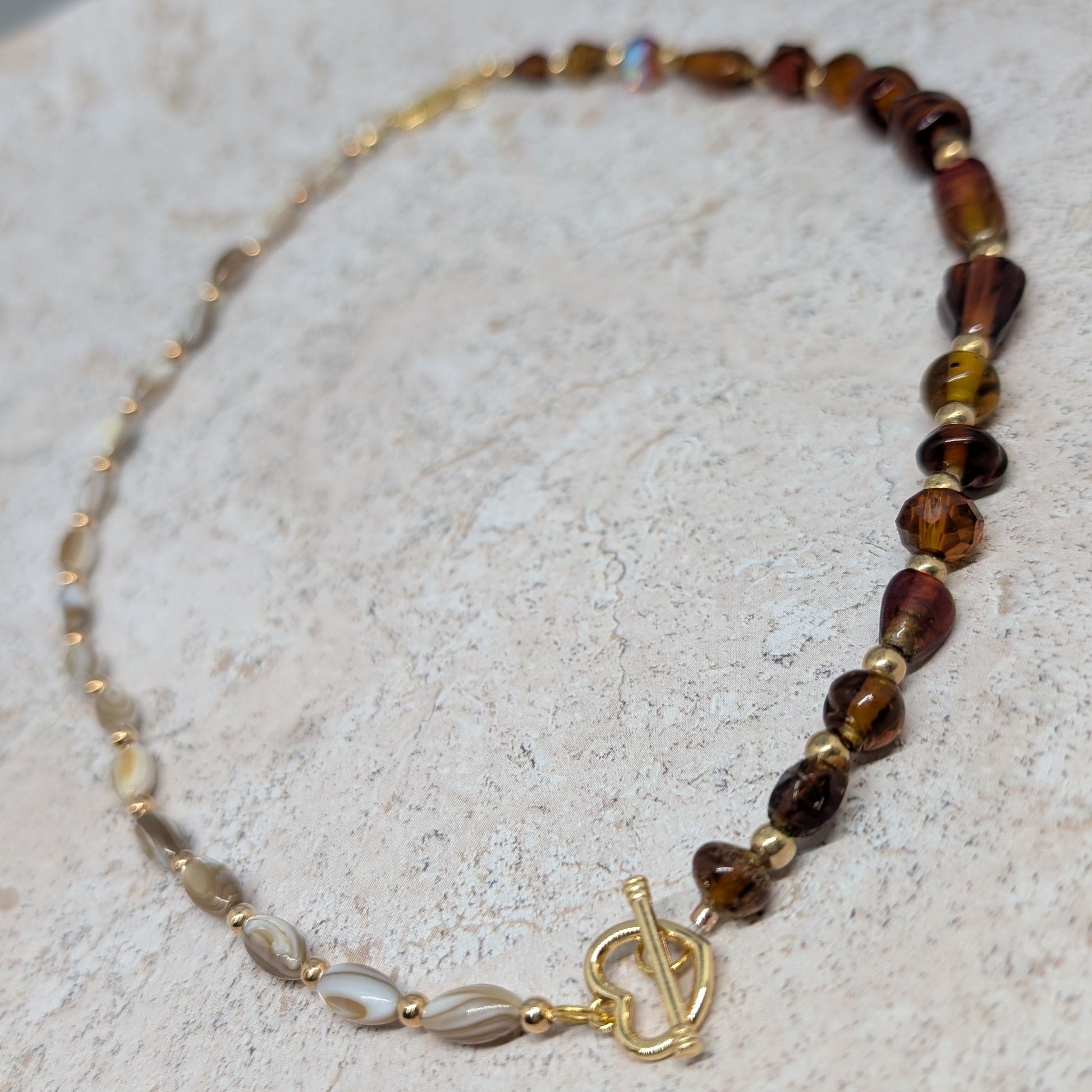 Beaded necklace with a gold clasp on a light stone surface