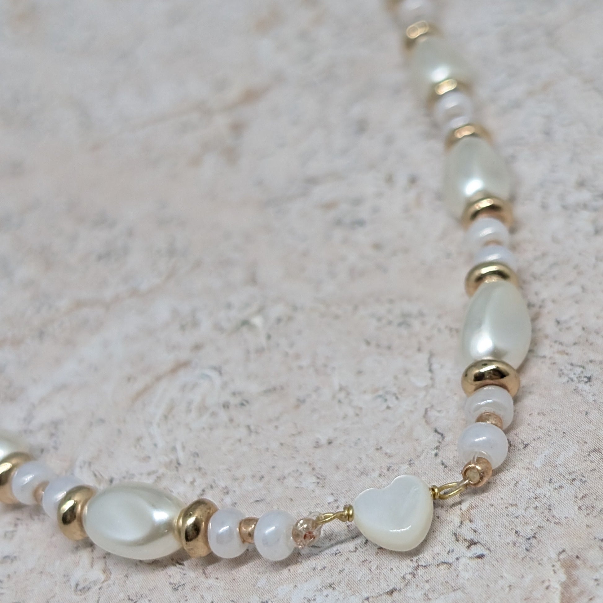 Pearl and gold beaded bracelet on a textured surface