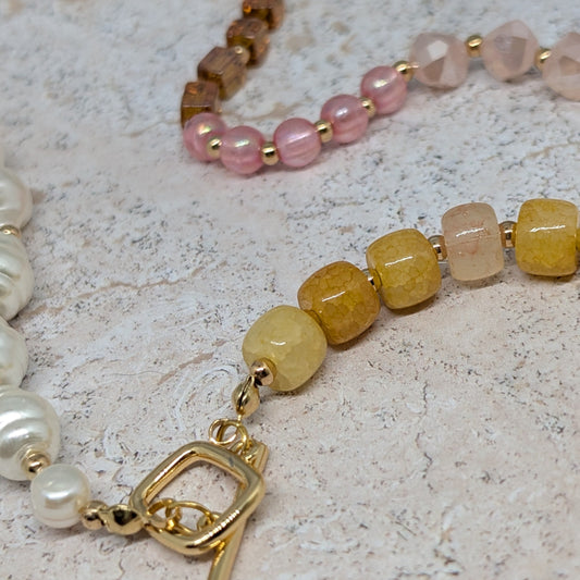 Close-up of a beaded bracelet with a gold clasp on a textured surface