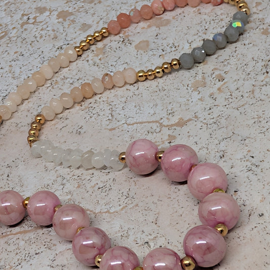Necklace with pink beads and gold accents on a textured surface
