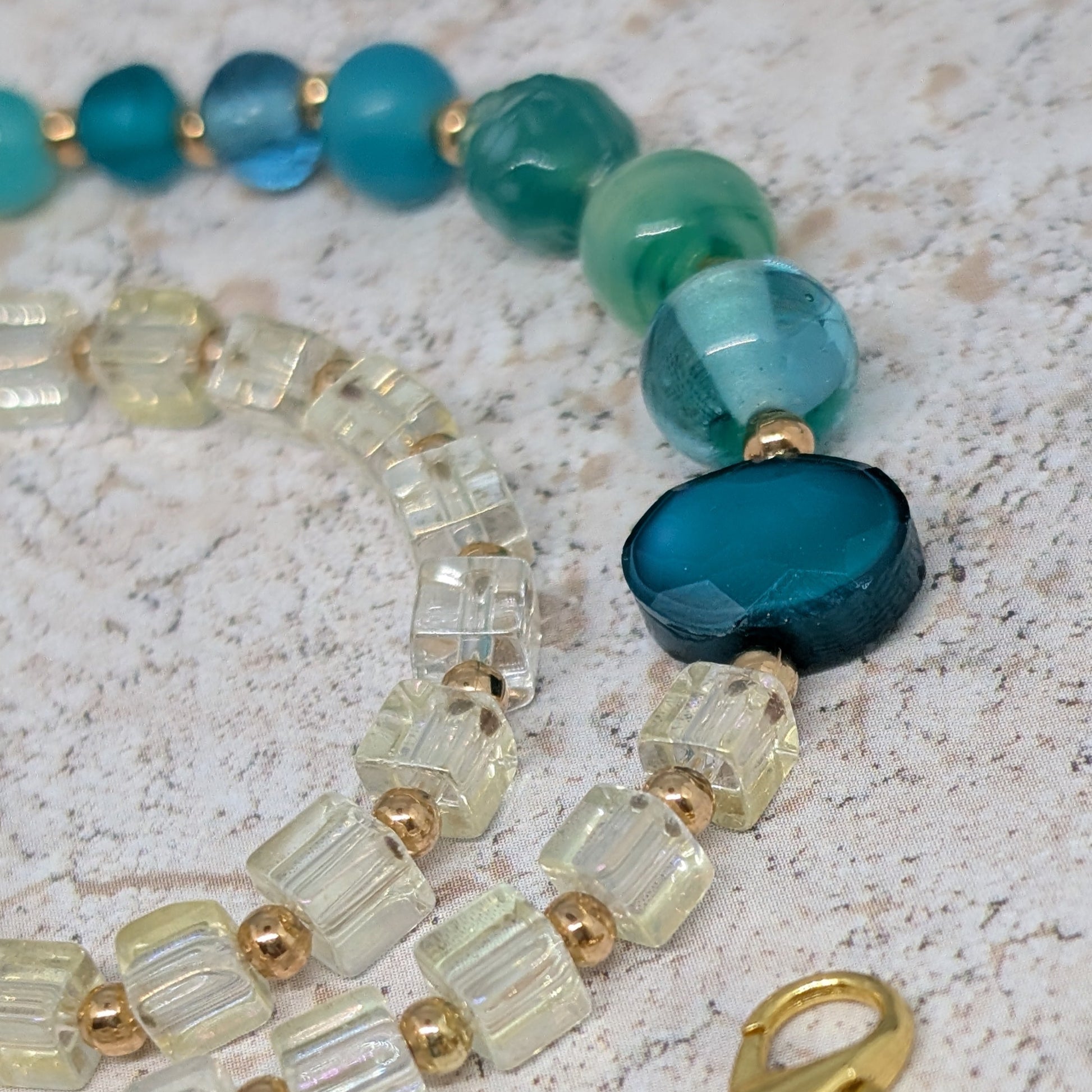 Beaded necklace with blue and green beads on a textured surface