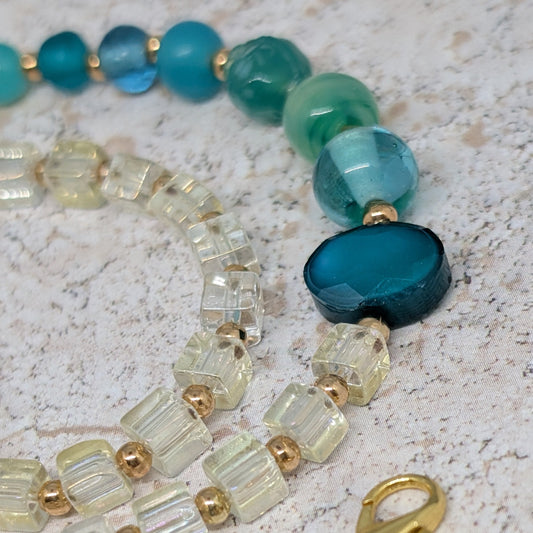 Beaded necklace with blue and green beads on a textured surface
