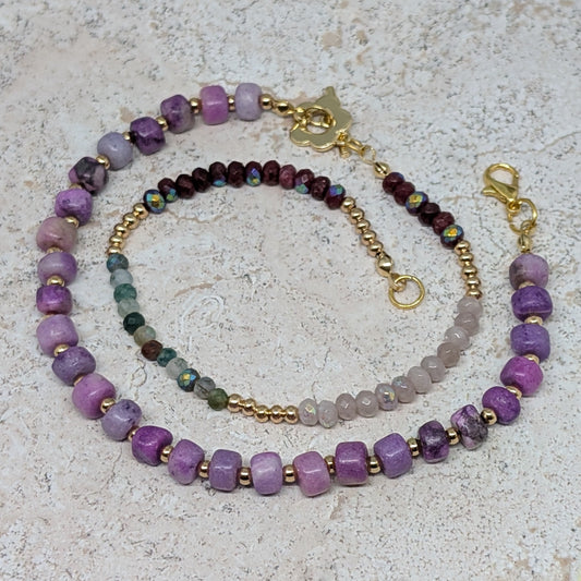Beaded necklace with purple and gold accents on a textured surface