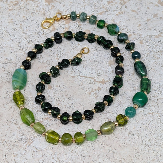 Necklace with green and black beads on a textured surface