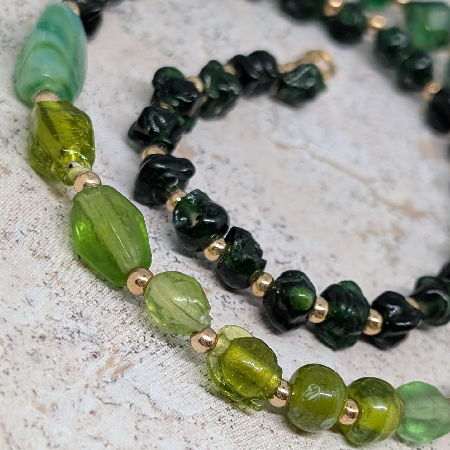 Necklace with green and black beads on a textured surface