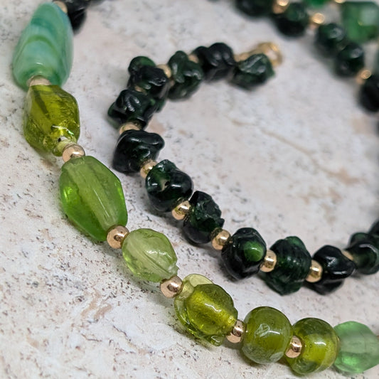 Necklace with green and black beads on a textured surface