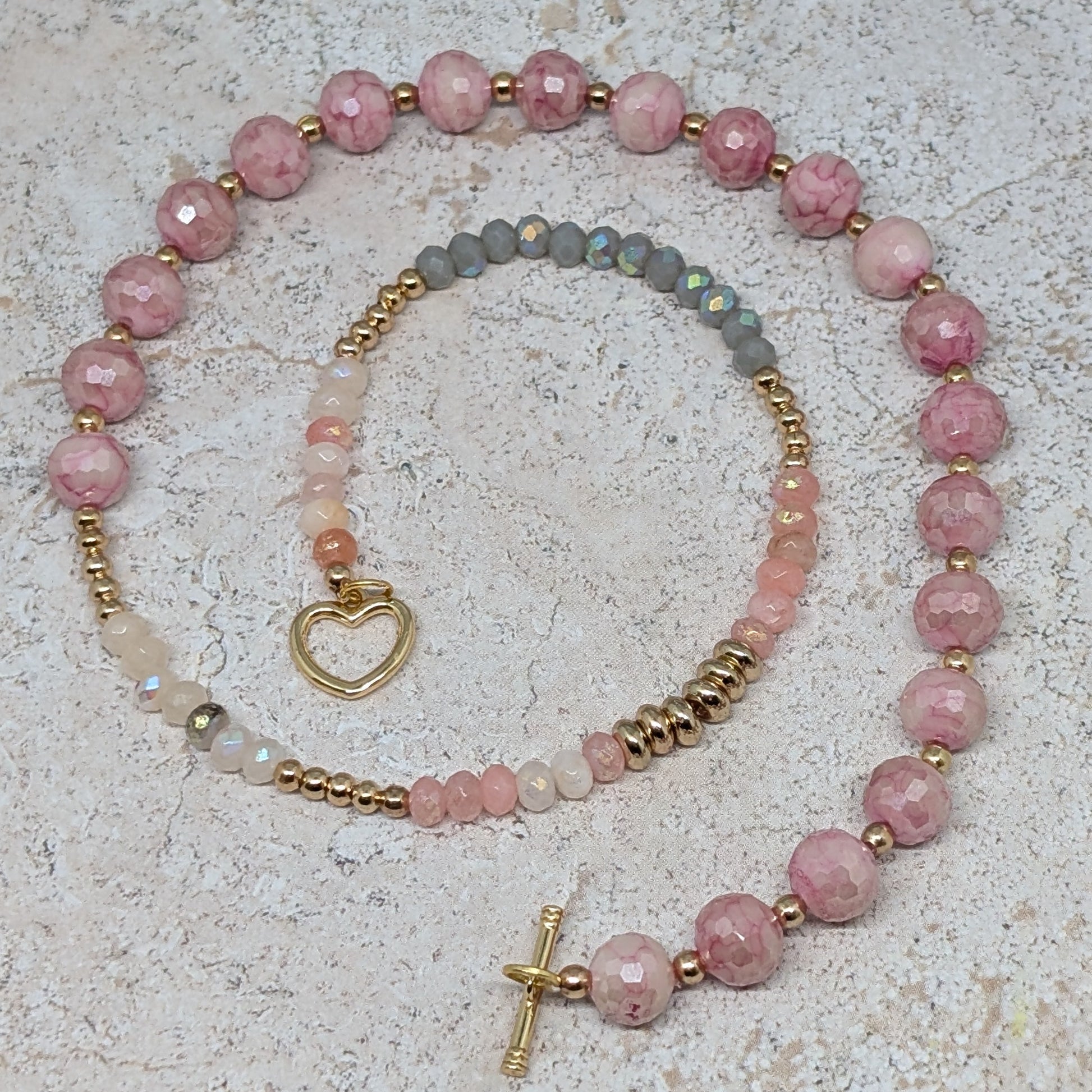 Necklace with pink beads and gold accents on a textured surface