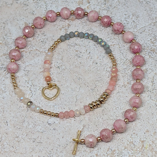 Necklace with pink beads and gold accents on a textured surface