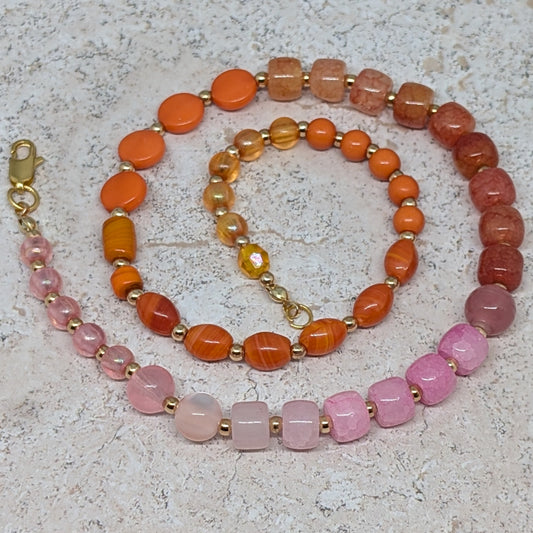 Necklace with orange, pink, and gold beads on a textured surface
