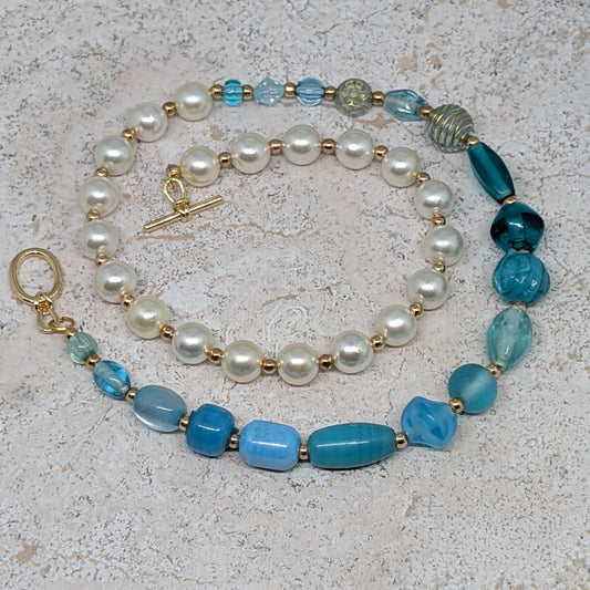 Necklace with pearls and blue beads on a textured surface