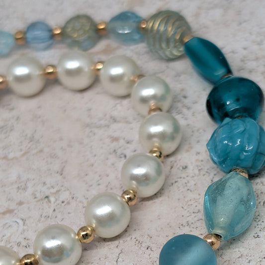 Beaded necklace with blue and white pearls on a textured surface