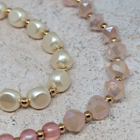 Set of three beaded bracelets with pink and white beads on a textured surface