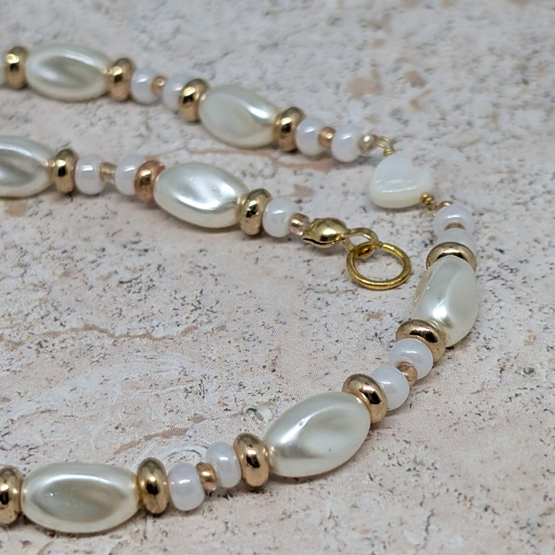 Pearl and gold beaded necklace on a textured surface
