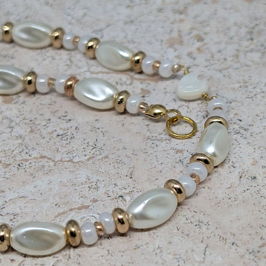 Pearl and gold beaded necklace on a textured surface