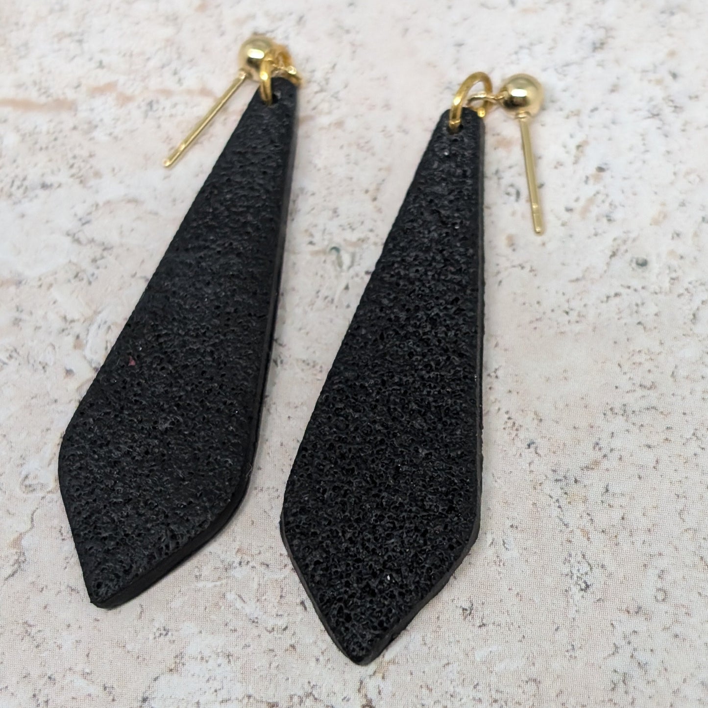 Black teardrop-shaped earrings on a light gray surface