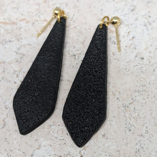 Black teardrop-shaped earrings on a light gray surface