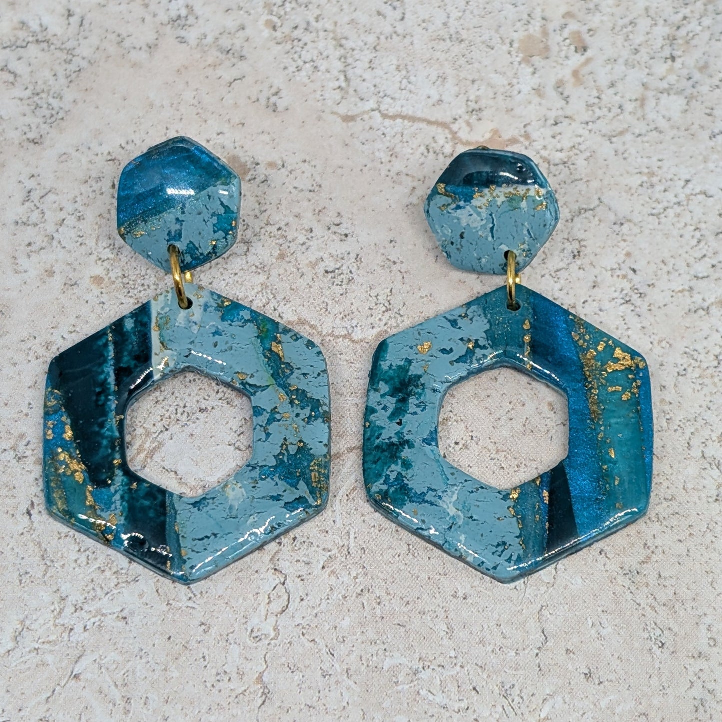Blue hexagonal earrings on a light gray surface