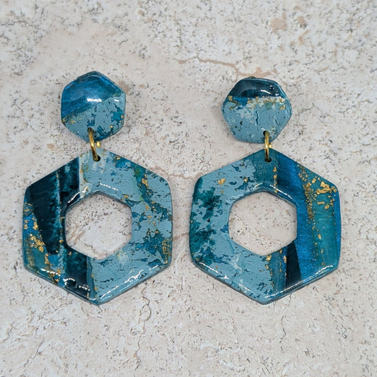 Blue hexagonal earrings on a light gray surface