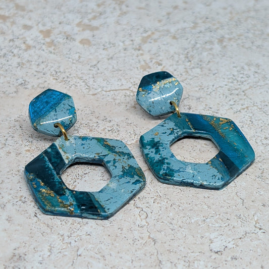 Blue geometric earrings on a light gray surface