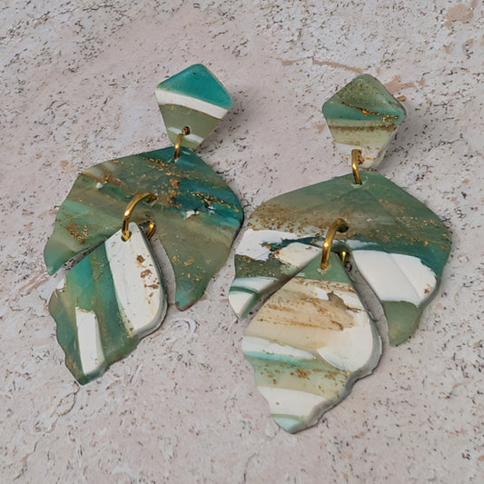 Pair of green and white earrings on a textured surface